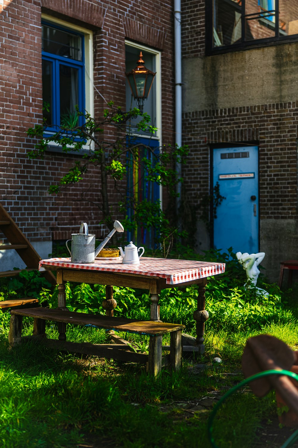 a picnic table with a tea pot on it in front of a brick building