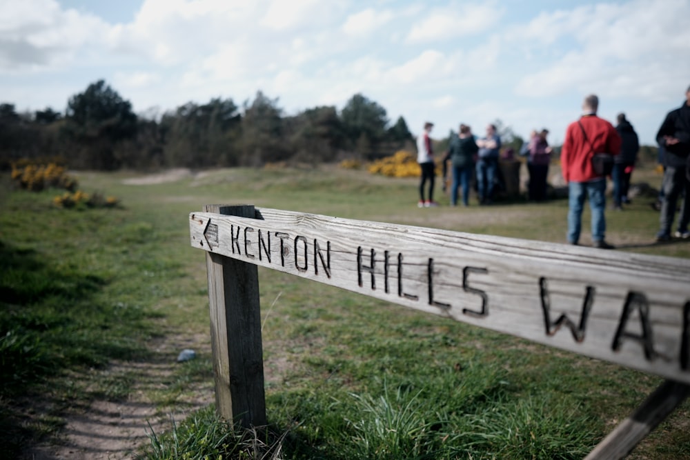 a group of people standing around a wooden sign