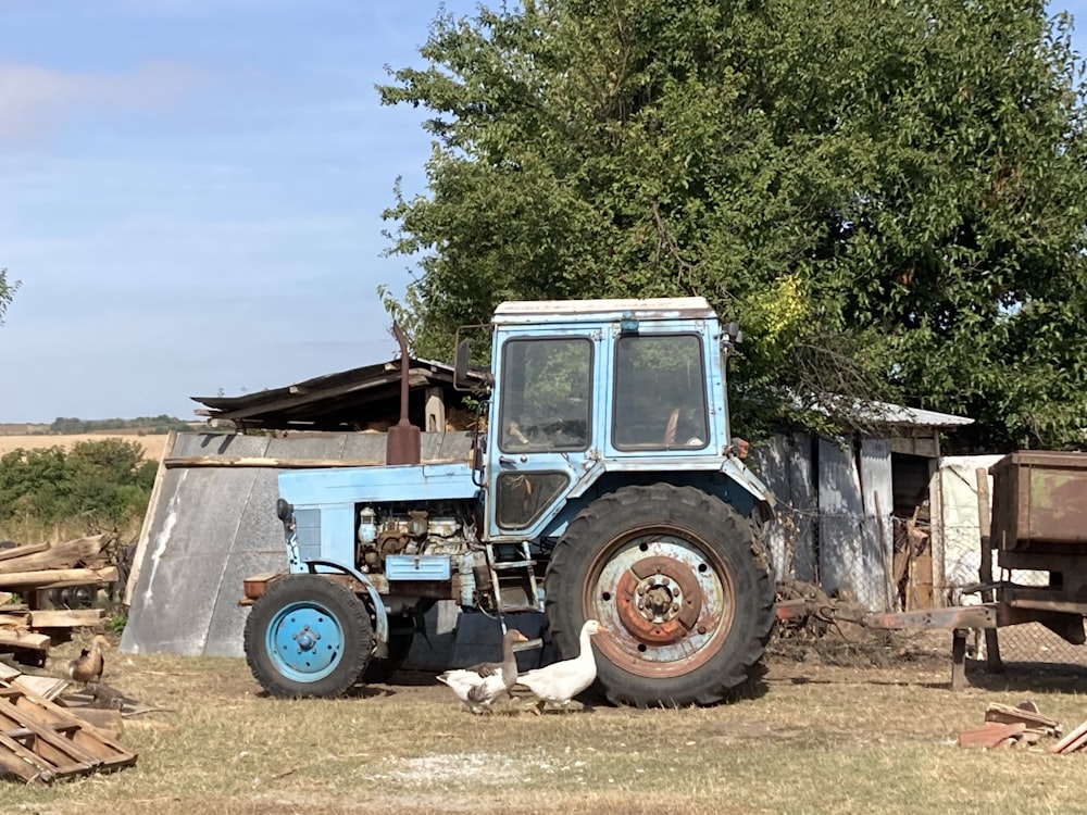 a blue tractor parked next to a pile of wood