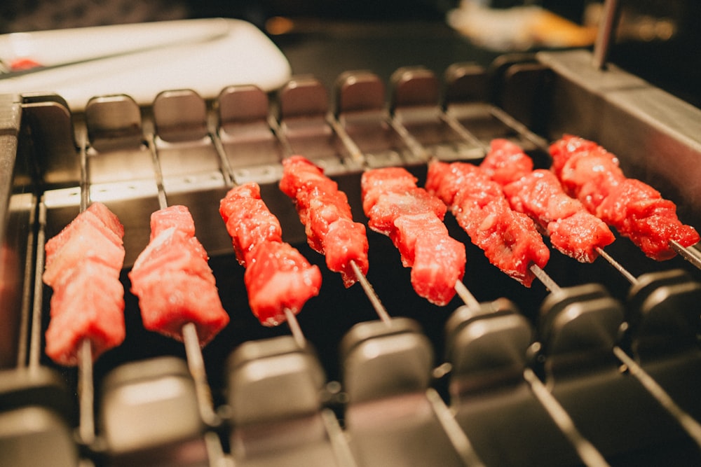 a close up of a grill with meat on skewers