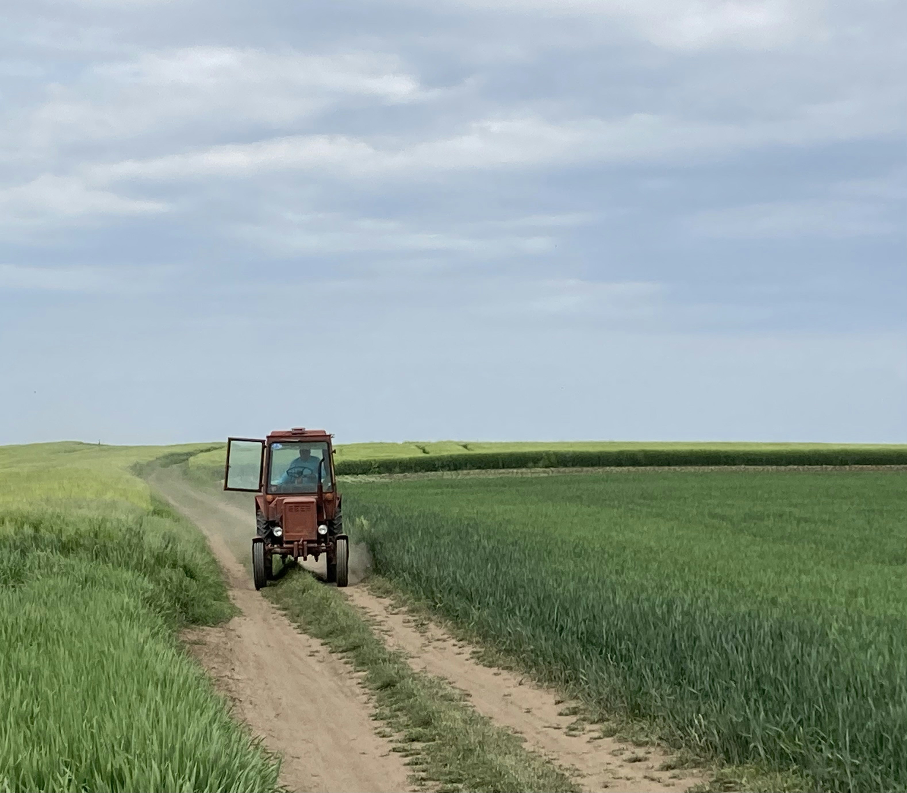 a tractor driving down a dirt road in a field