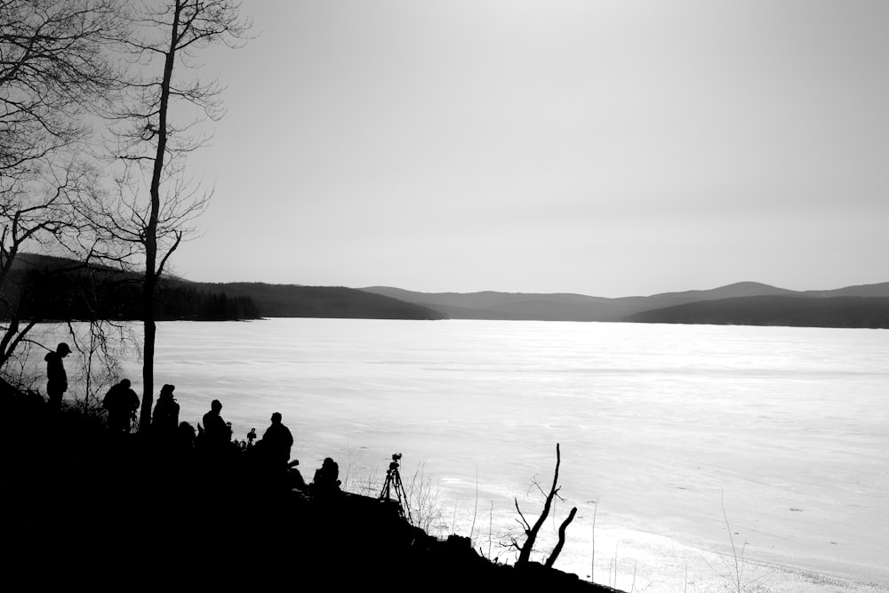 a group of people standing on top of a hill next to a body of water