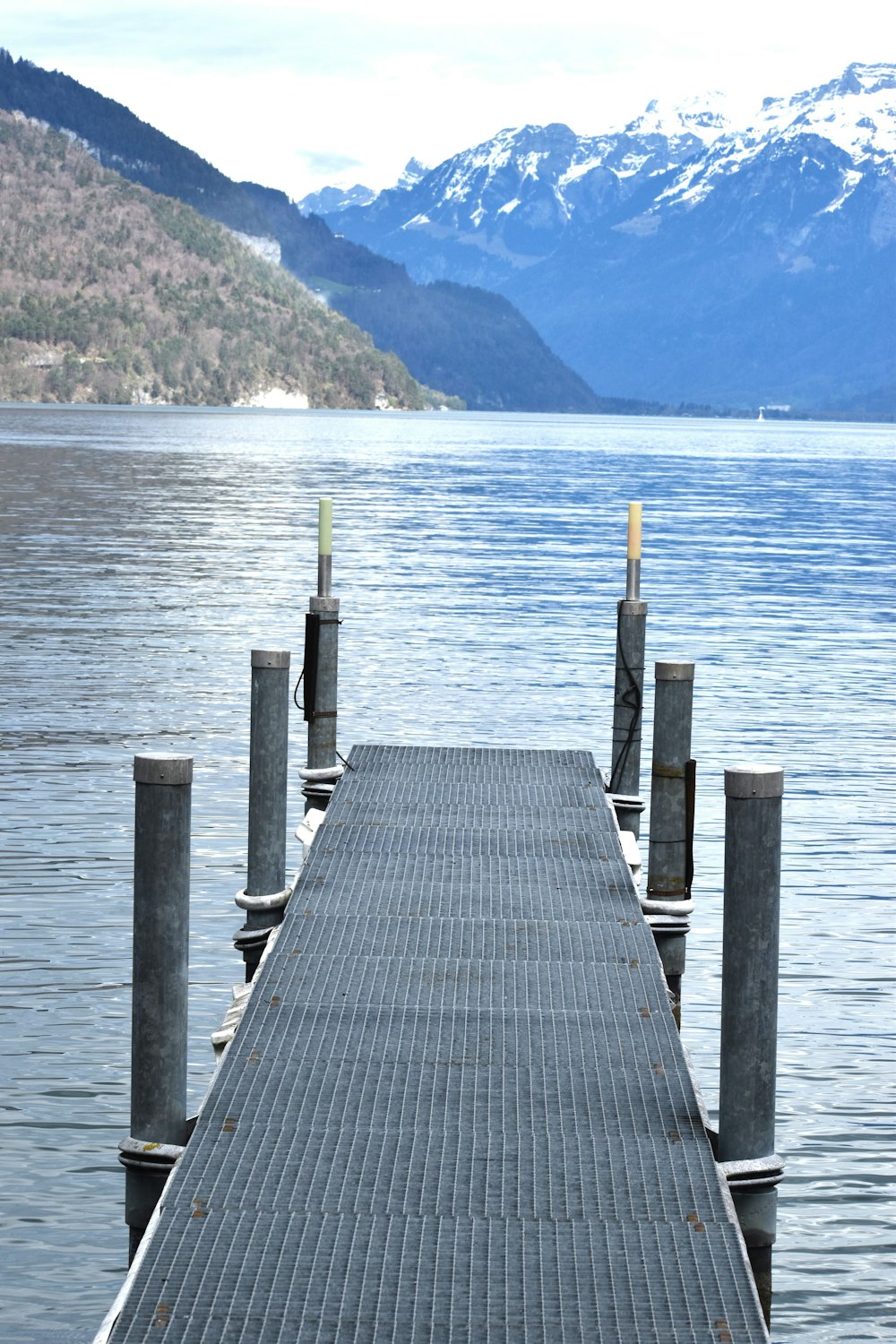 a long dock on a lake with mountains in the background