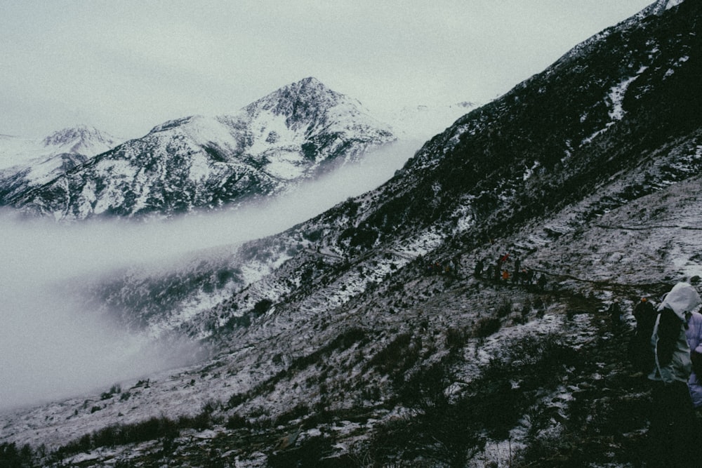 a group of people walking up the side of a snow covered mountain