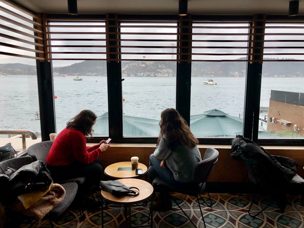 a couple of women sitting next to each other near a window