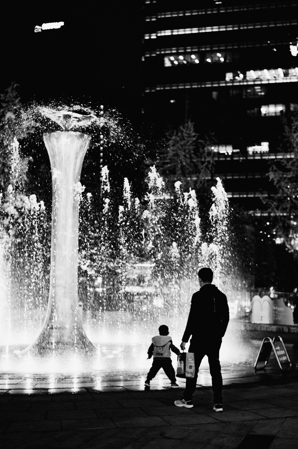 a black and white photo of a man and a child walking in front of a