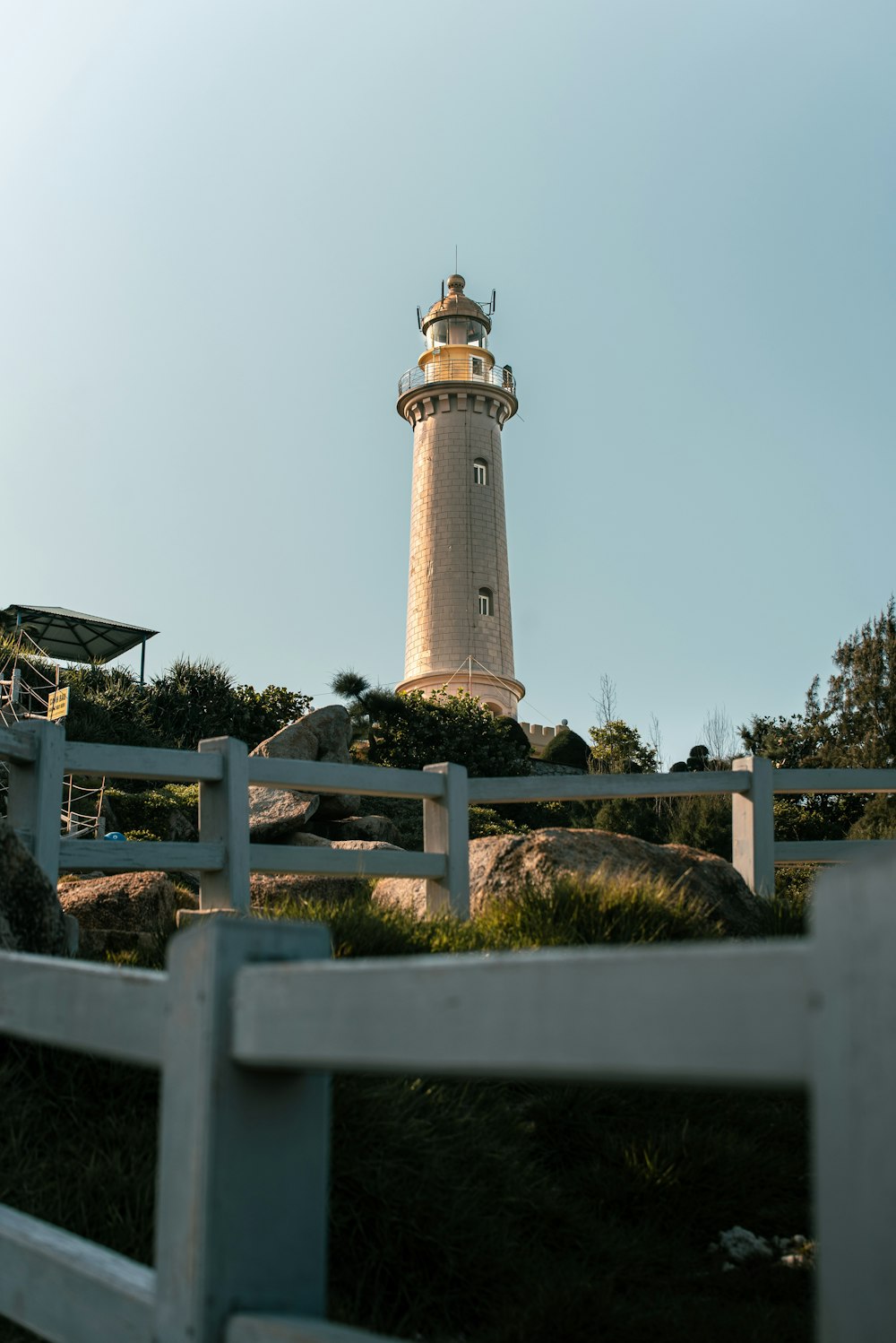 a white fence with a light house in the background