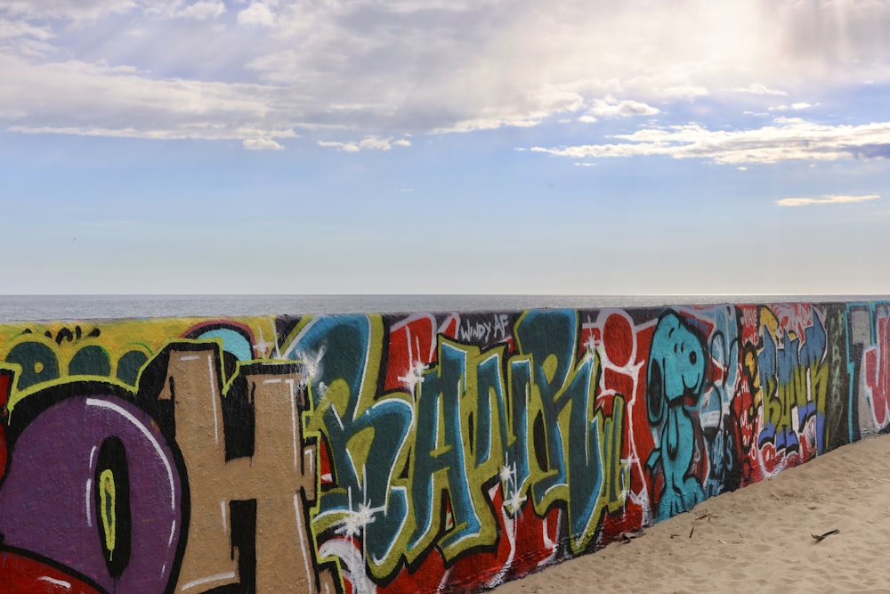 a wall covered in lots of graffiti next to the ocean