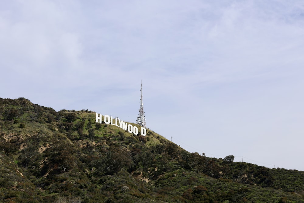 the hollywood sign atop a hill with a radio tower in the background