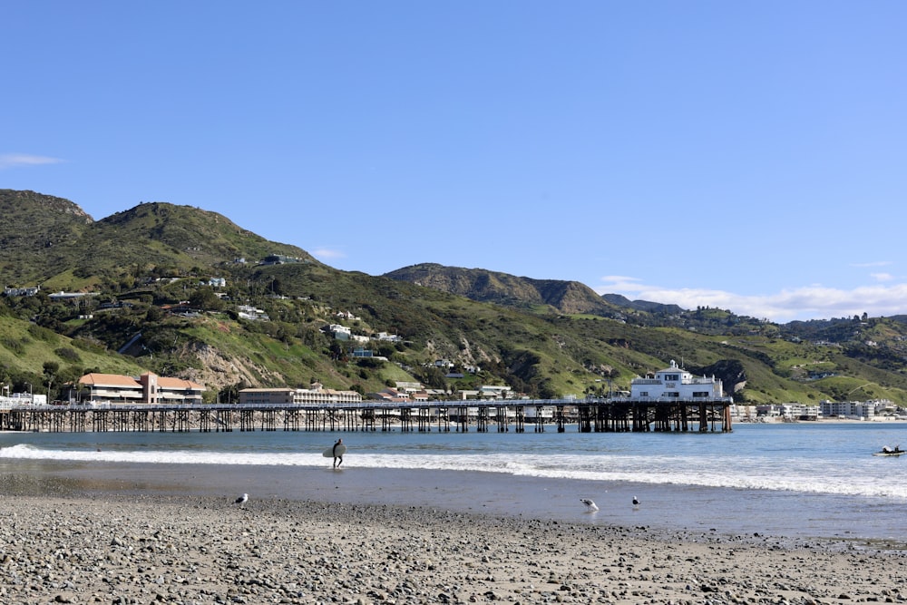 a person walking on a beach near a pier