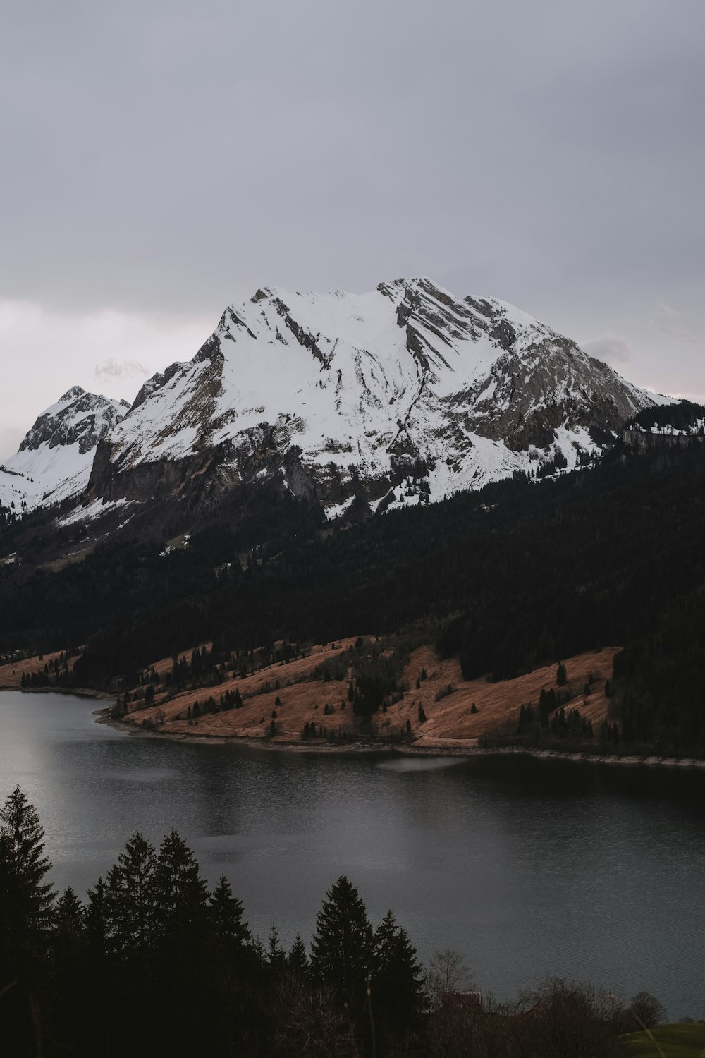 a snow covered mountain with a lake in the foreground