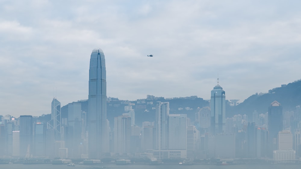 a plane flying over a large city in a foggy sky