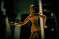a wooden doll standing in a dark room