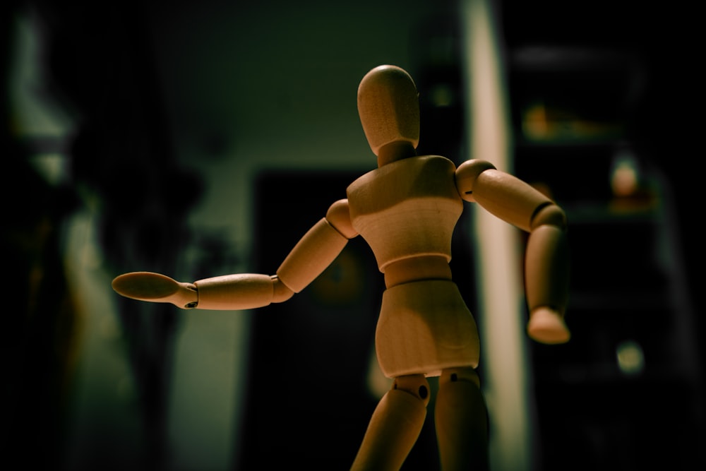 una bambola di legno in piedi in una stanza buia