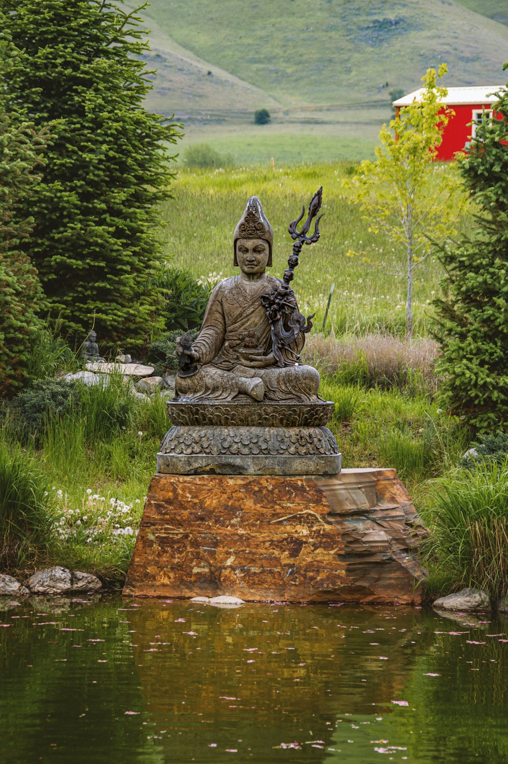 a statue of a buddha sitting in a pond