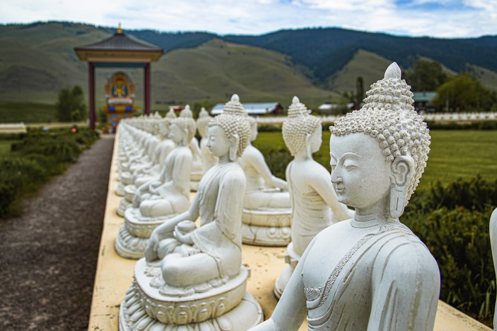 a row of buddha statues sitting on top of a cement slab