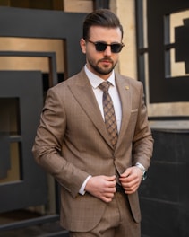a man in a suit and sunglasses standing in front of a building