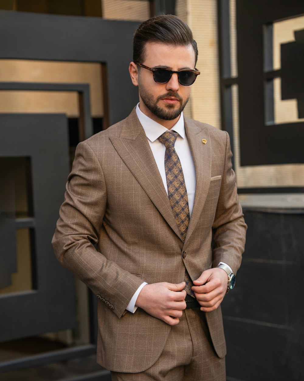 a man in a suit and sunglasses standing in front of a building