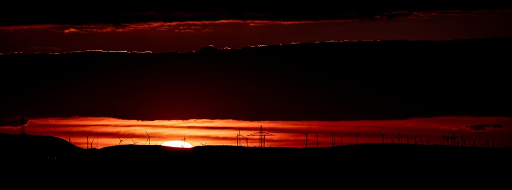 the sun is setting over a field of windmills