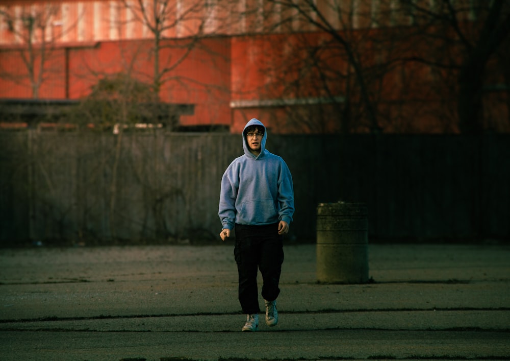 a man in a blue hoodie is walking down the street