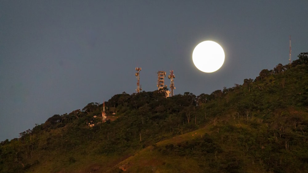 a full moon is seen over a hill