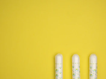 three toothbrushes sitting on top of a yellow surface