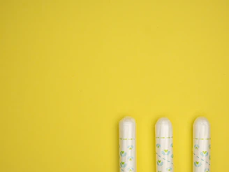 three toothbrushes sitting on top of a yellow surface