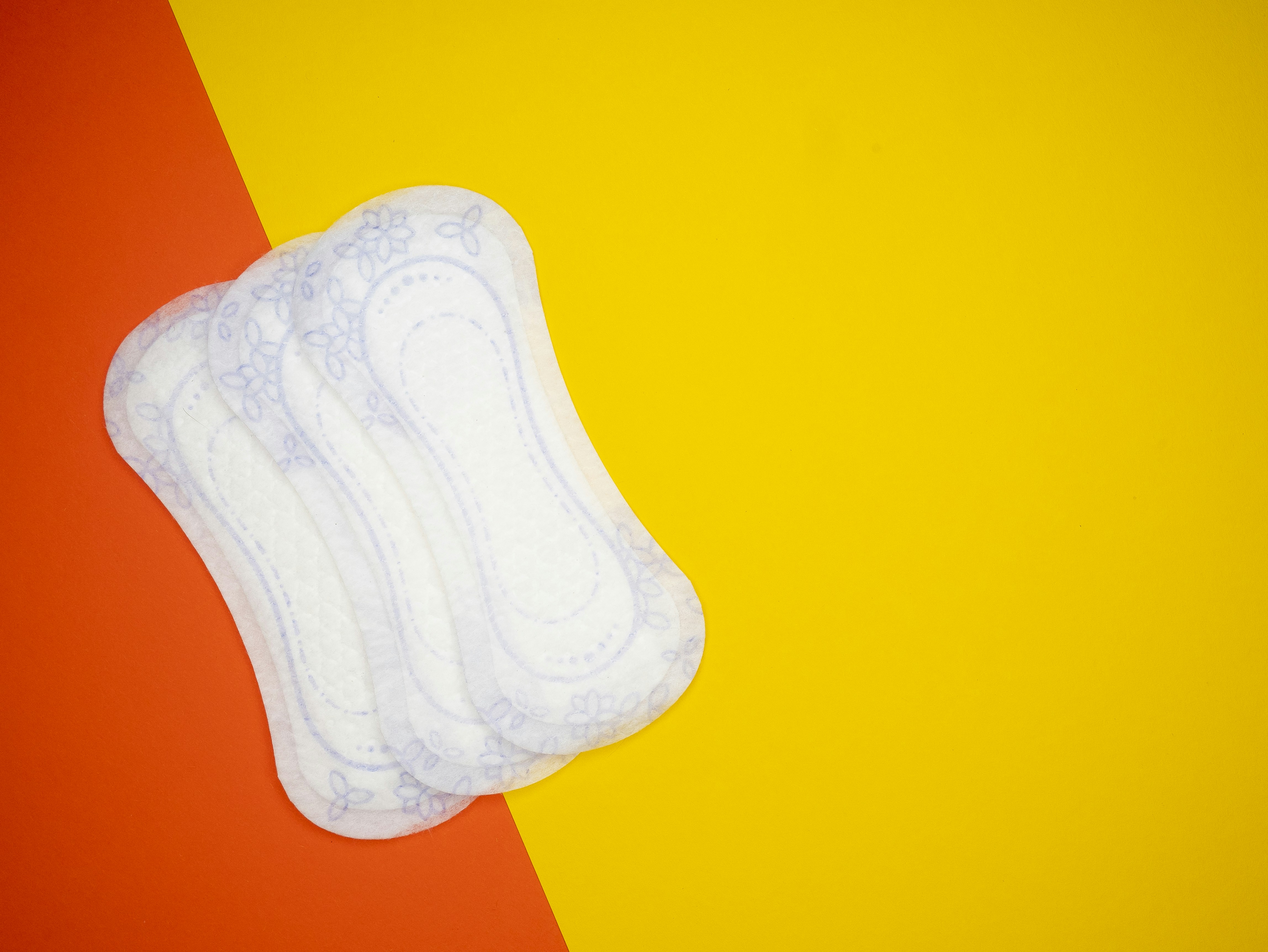 a pair of sanitary pads sitting on top of a yellow and red background