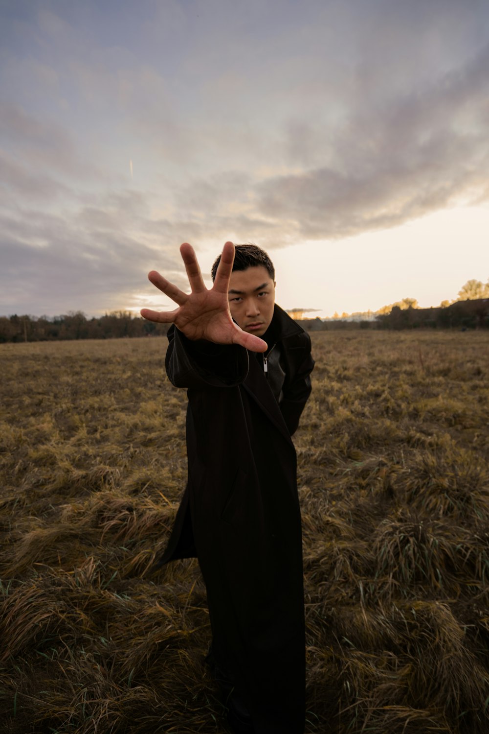 a man standing in a field holding his hand up