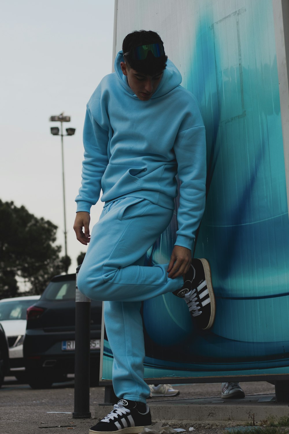 a man in a blue sweat suit leaning against a blue wall