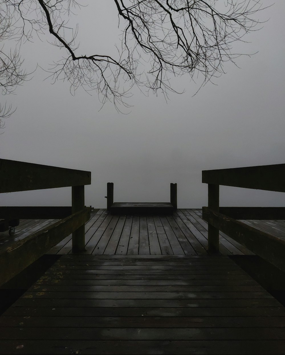 a wooden dock with benches on a foggy day