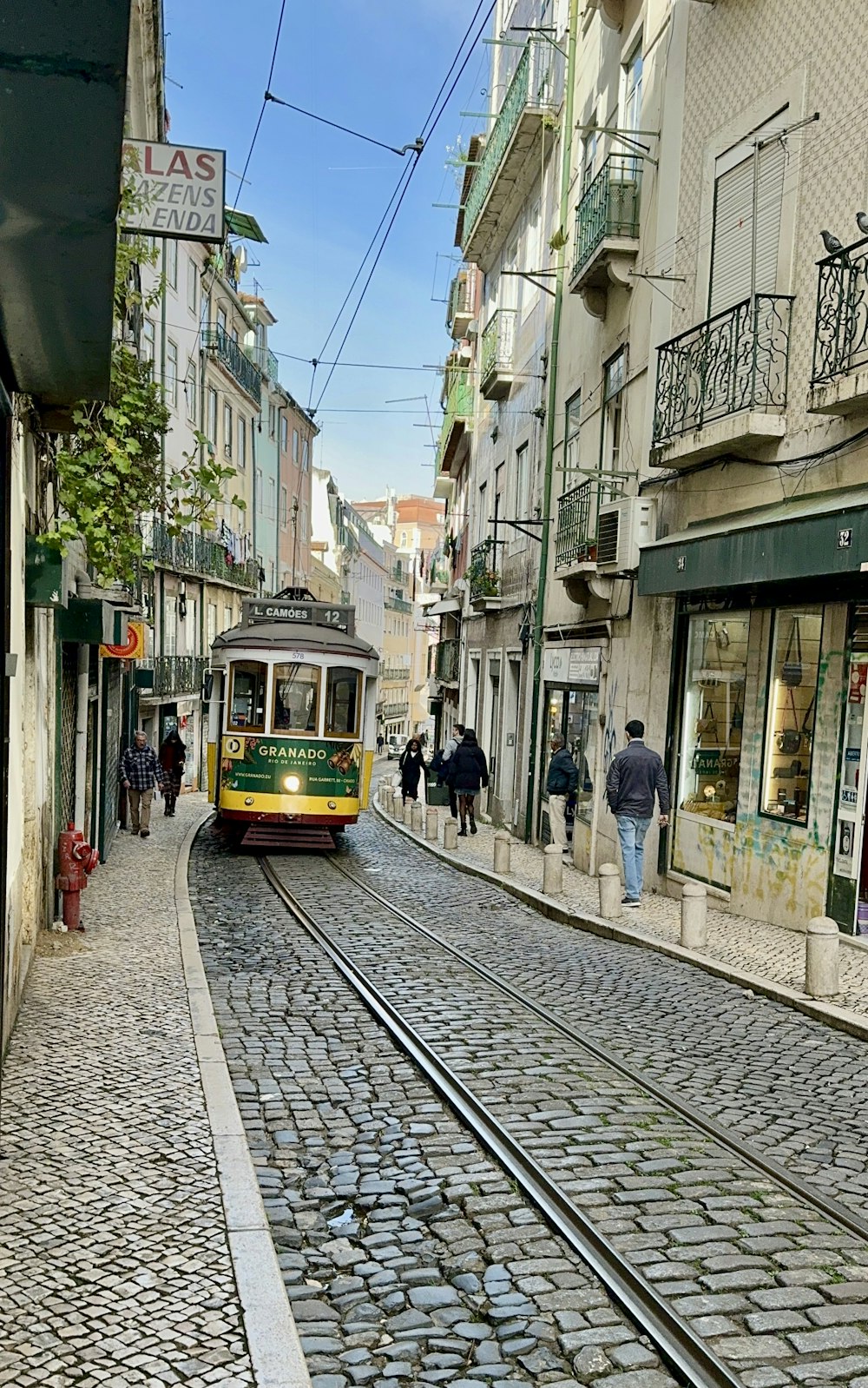 a trolley on a city street with people walking on the sidewalk