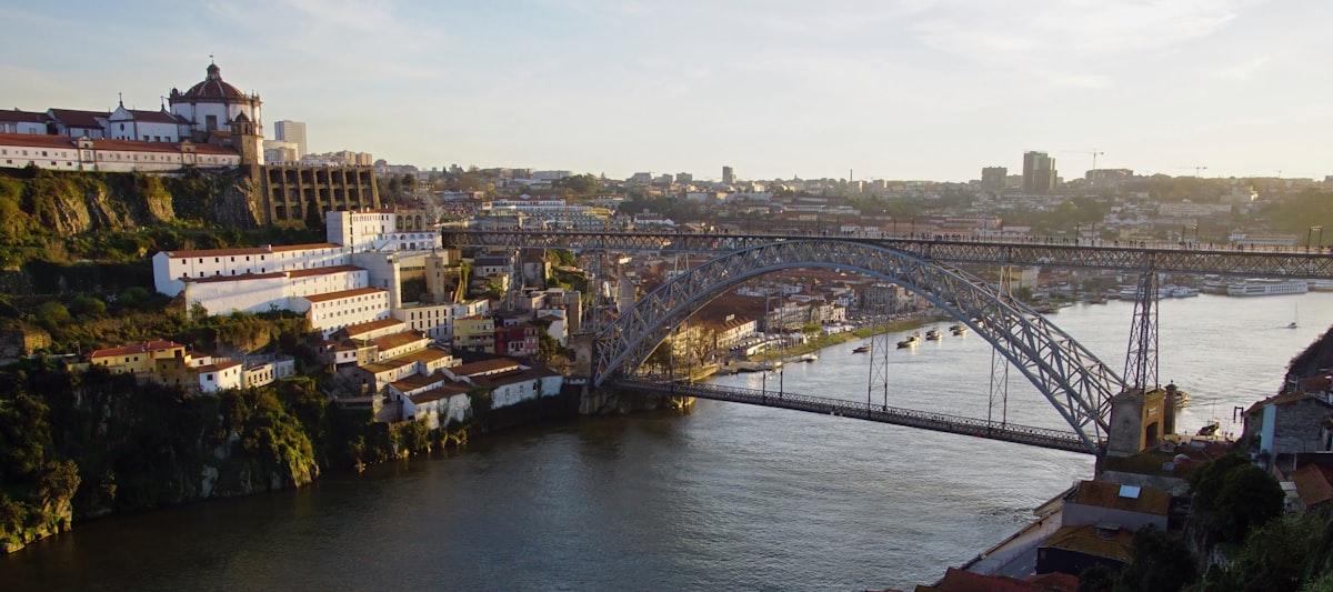 Porto May — the Dom Luís I bridge spanning the Douro River at dusk, city lights beginning to glow