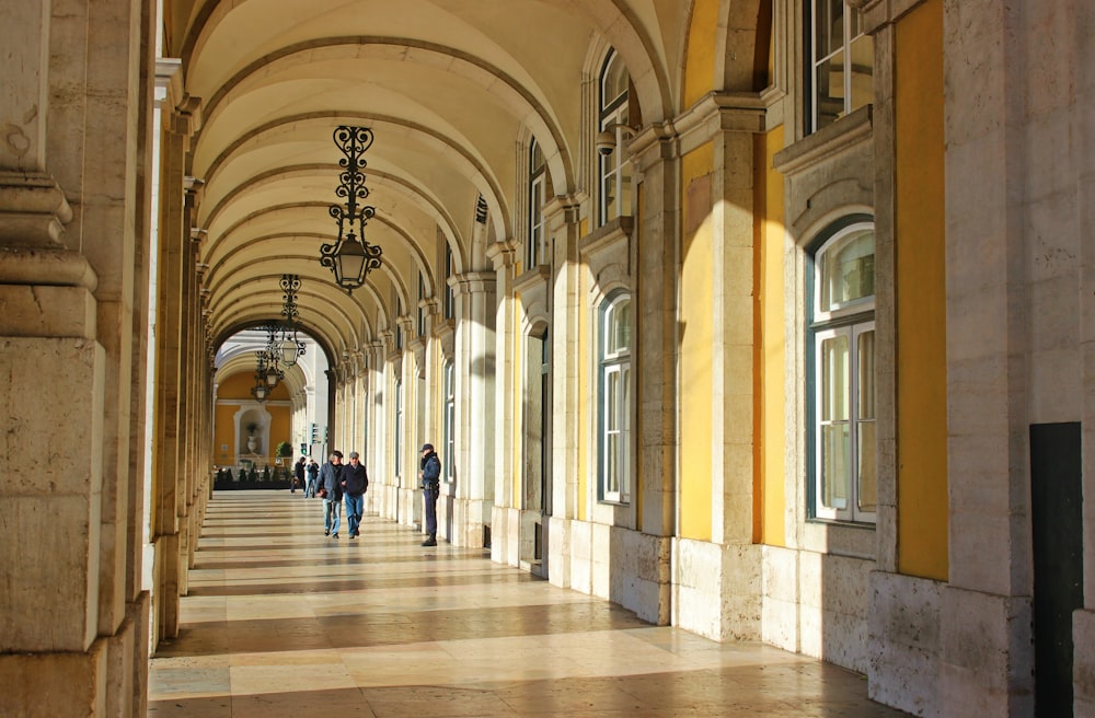 a group of people walking down a hallway between two buildings