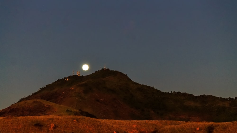 a hill with a full moon in the sky