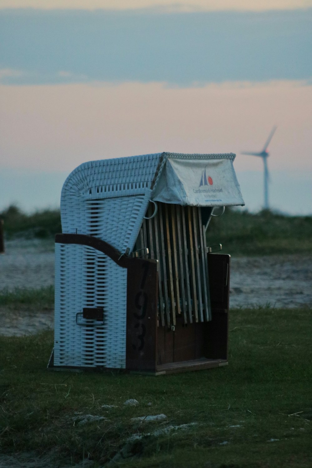 a white outhouse with a wind turbine in the background