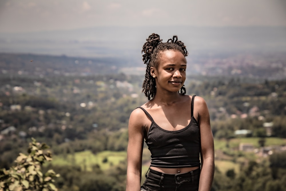 a woman standing on top of a lush green hillside