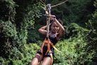 a woman on a zip line in the jungle