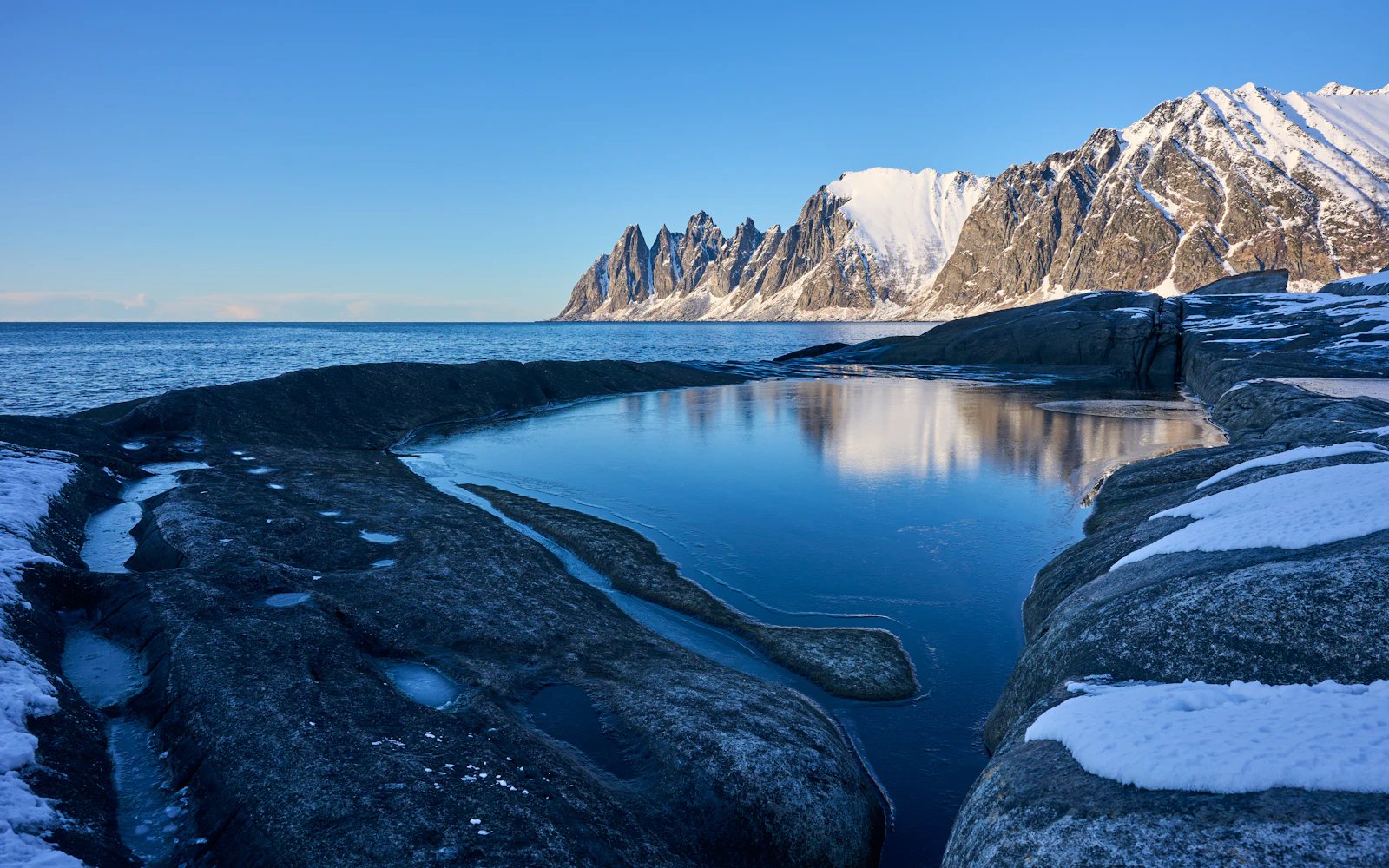 The jagged Okshornan peaks seen across the water from Tungeneset — Senja, Norway