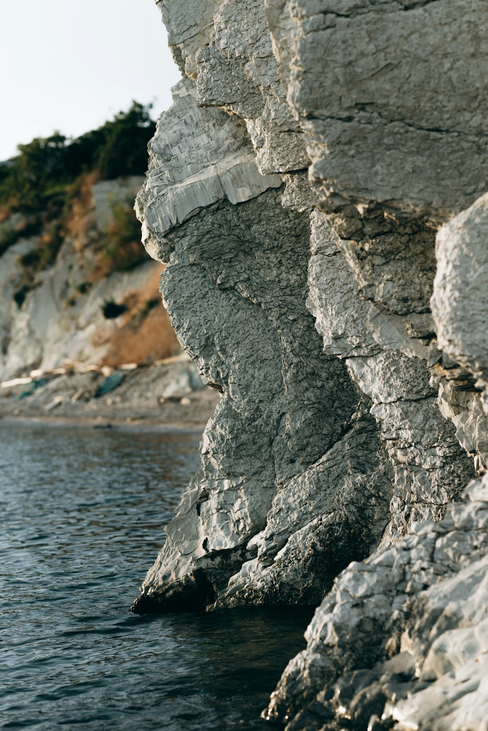 a rocky cliff with a body of water in the foreground