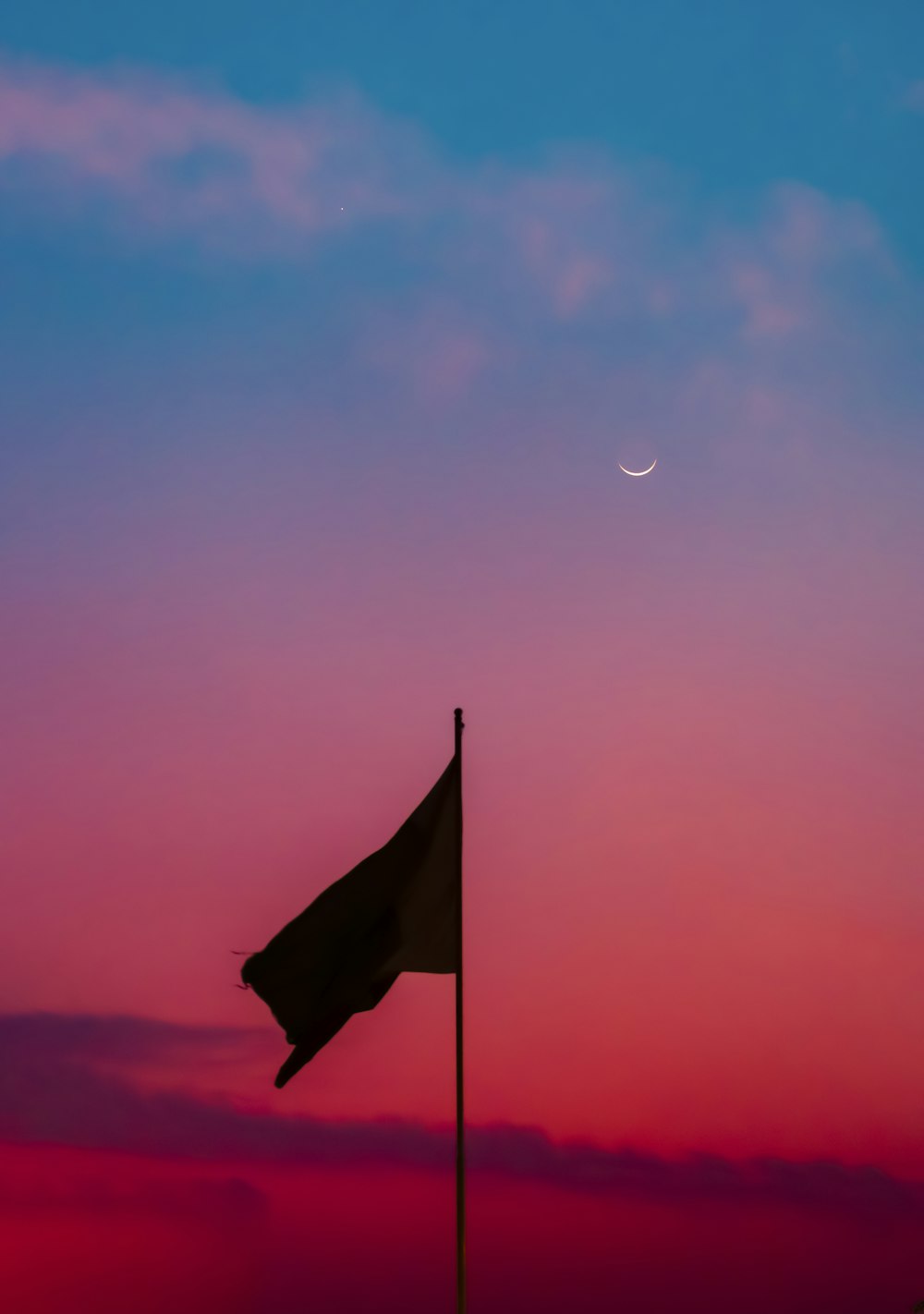 a flag on a pole with the moon in the background