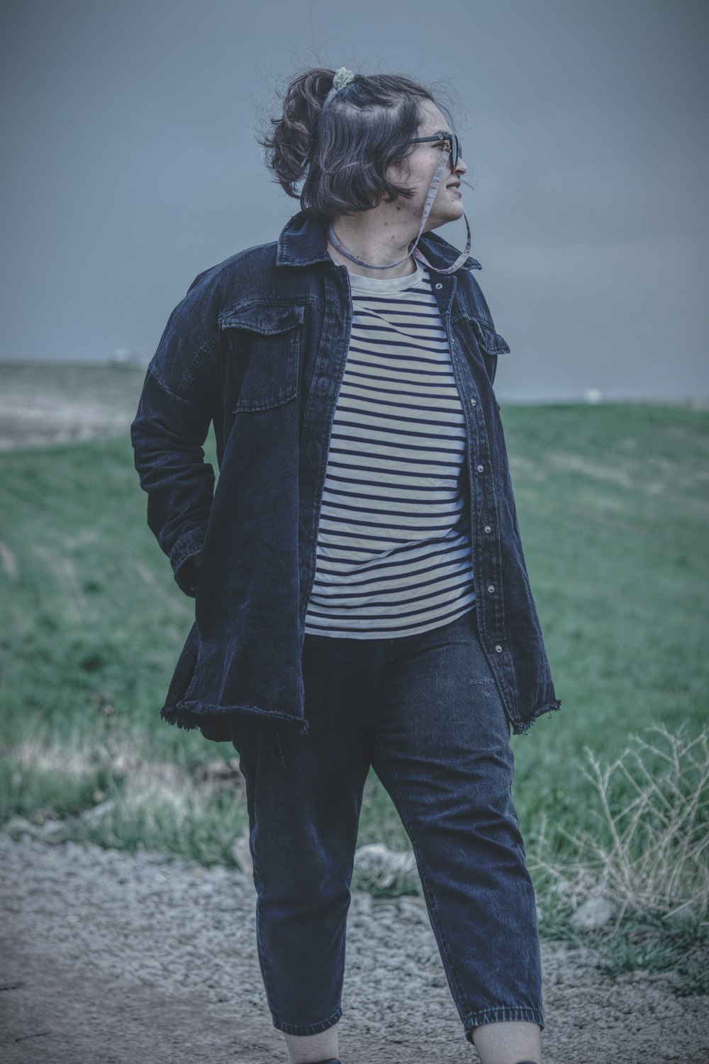 a woman standing in a field with her hands in her pockets