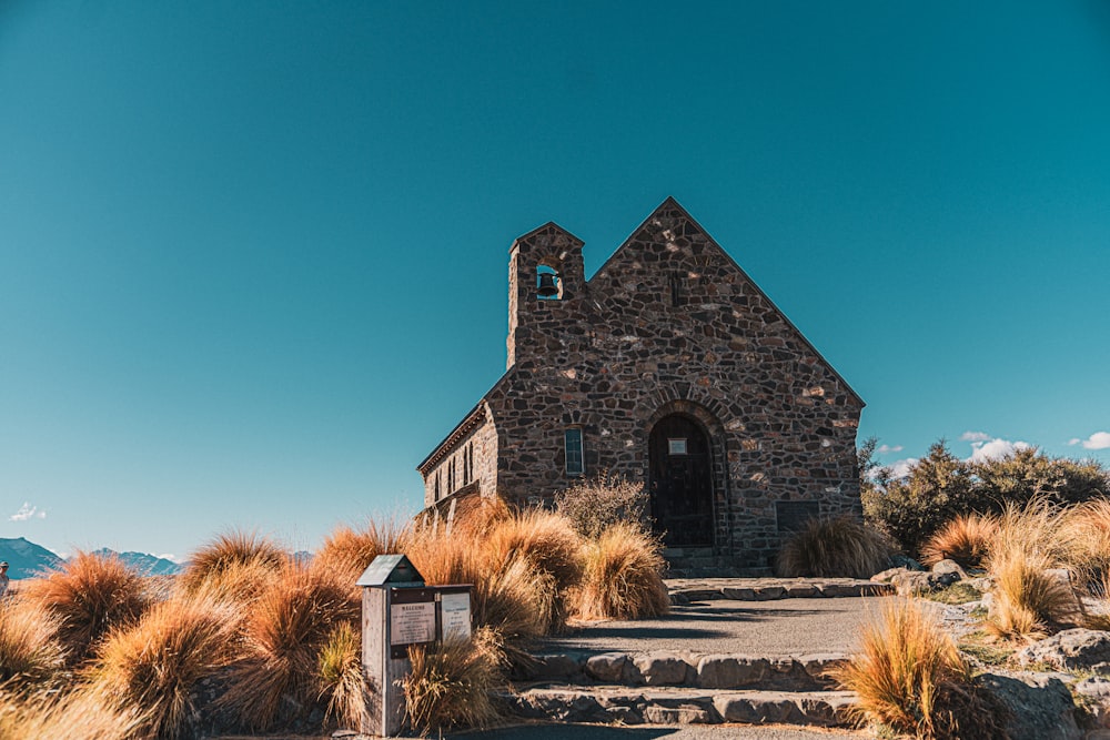 a stone church with a steeple surrounded by grass