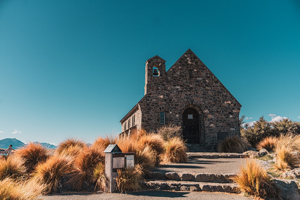 a stone church with a steeple surrounded by grass