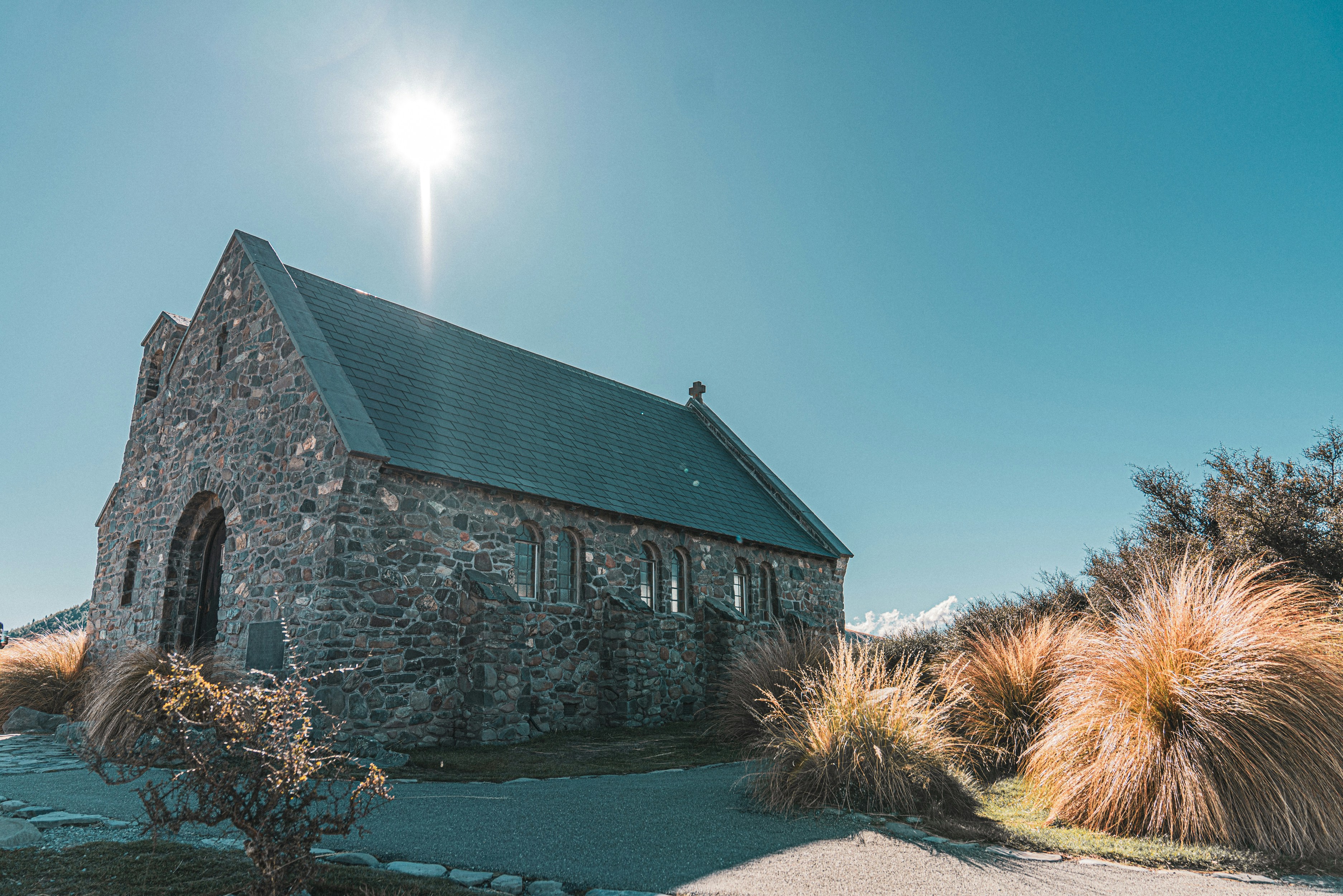 a stone church with a steeple surrounded by grass