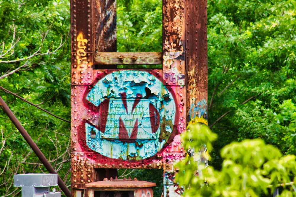 a rusted out sign sitting in the middle of a forest