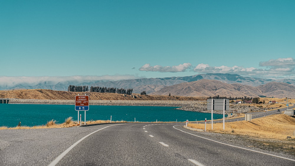 a sign on the side of a road near a body of water