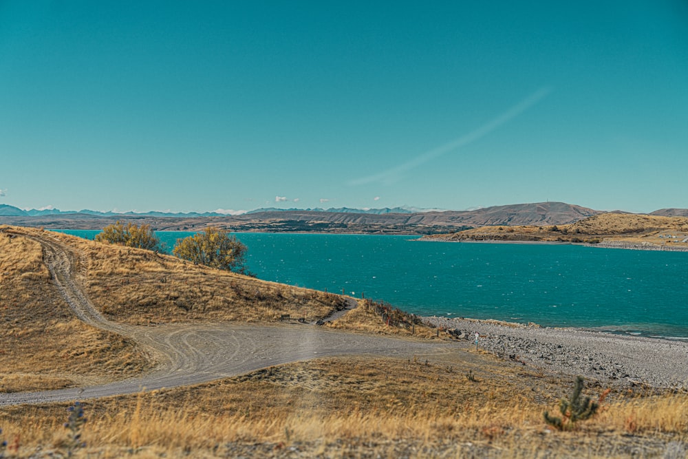 a scenic view of a lake and a dirt road