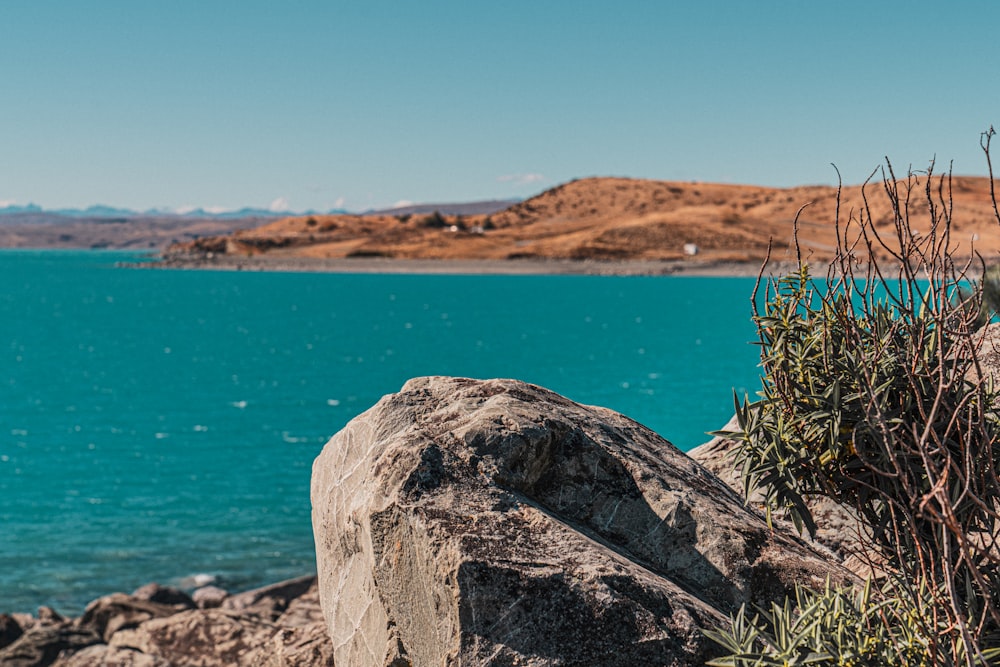 a large rock sitting on top of a beach next to a body of water