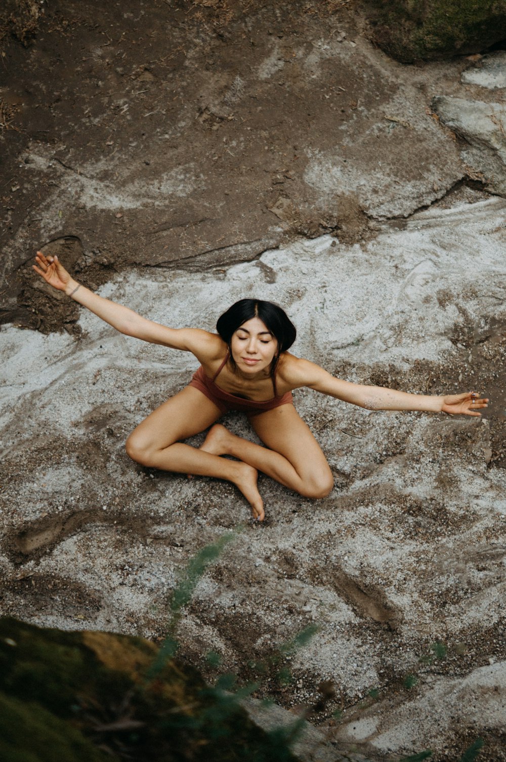 a woman in a bikini sitting on a rock